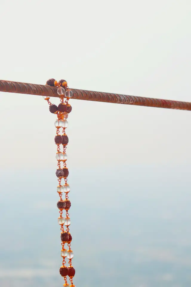 A rudraksha mala hanging from a wooden rod
