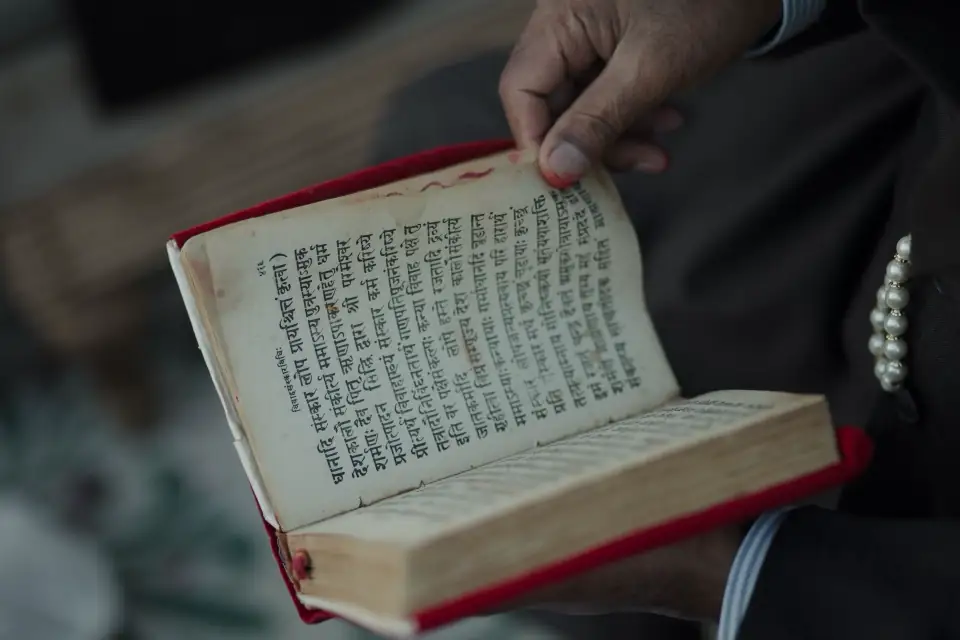 Hands holding an old Sanskrit book